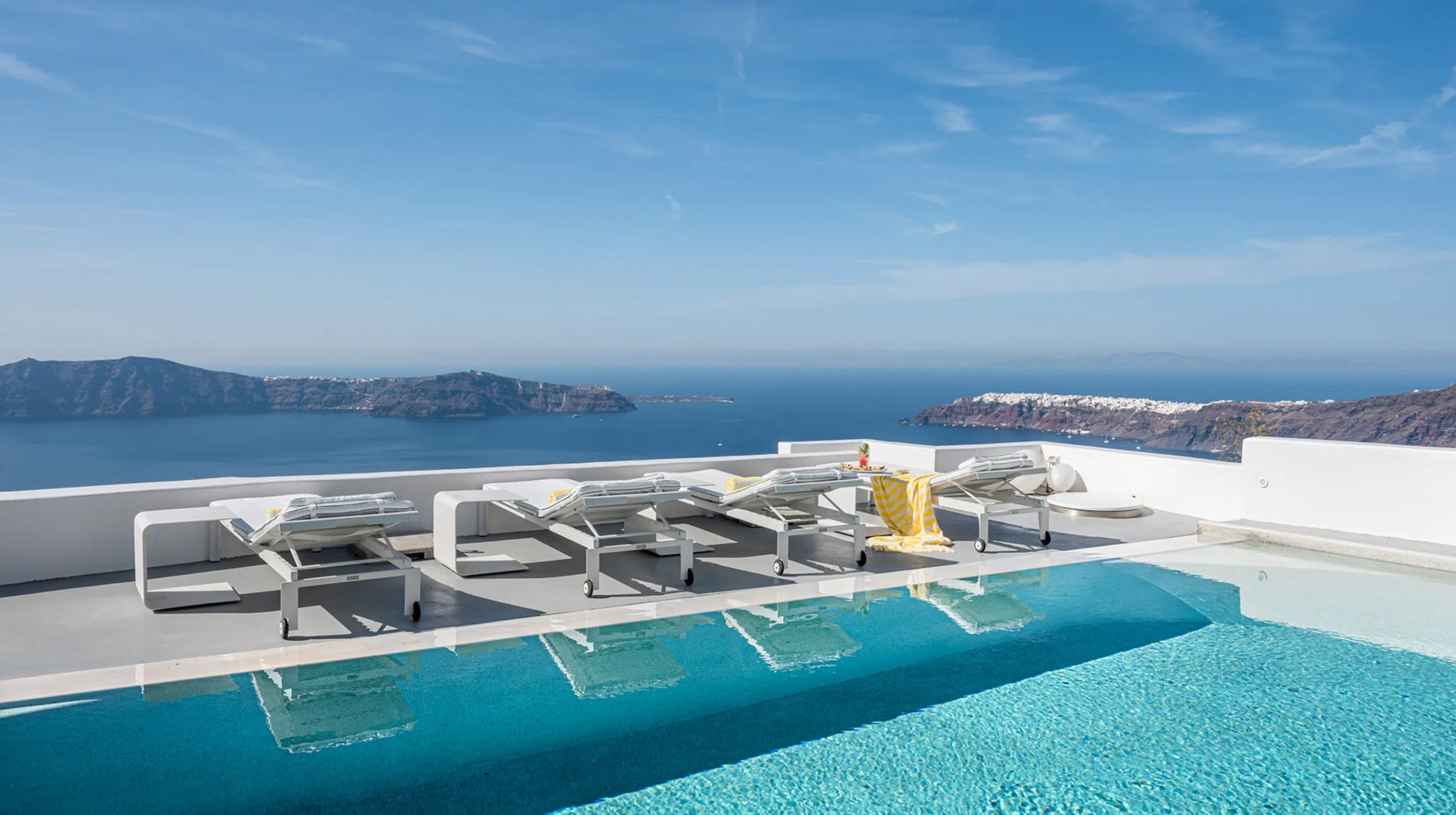 Guests relaxing by the largest infinity pool on Santorini at Grace Hotel – discover exclusive Member rates with CountryClubuk