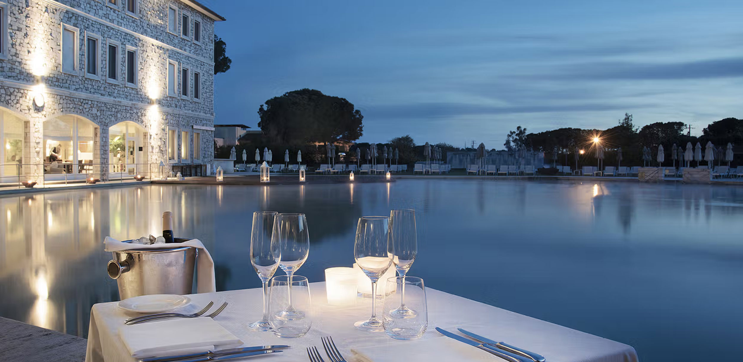 1919 Restaurant at Terme di Saturnia with tables overlooking the illuminated thermal spring pools