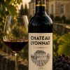 Château Lyonnat 2016 Lussac-Saint-Émilion Bordeaux with glass of red wine overlooking the château vineyards at sunset.