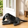 Dora Designs Cocker Spaniel doorstop lying beside a wooden door
