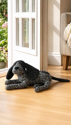 Dora Designs Cocker Spaniel doorstop lying beside a wooden door