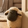 Dora Designs Lois the Lamb sheep doorstop beside an open doorway